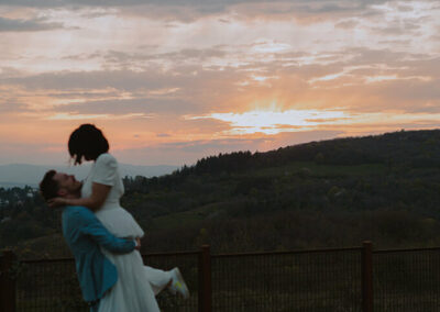 couple de jeunes mariés s'enlaçant devant un coucher de soleil